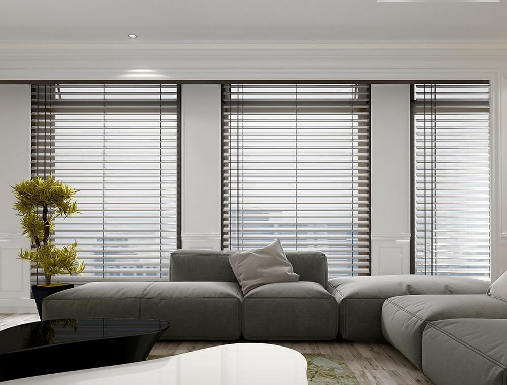 Moderne Innenbeschattung an den Fenstern eines Wohnzimmers mit einer großen, grauen Wohnlandschaft